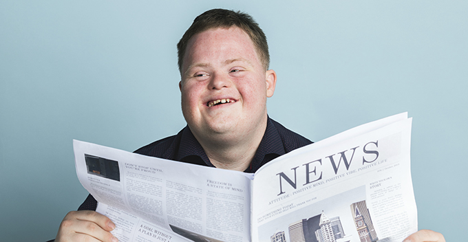 boy with Down syndrome reading a newspaper