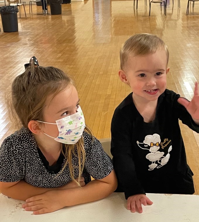 Baby waving with sister wearing mask