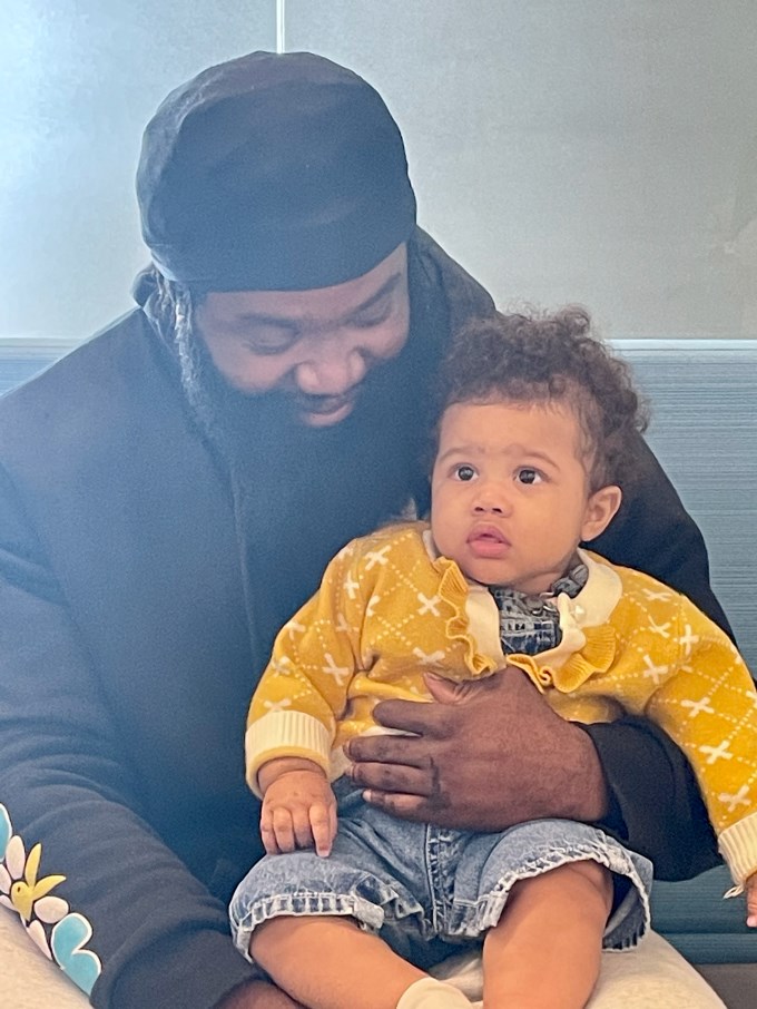 man with beard holding his baby in yellow sweater