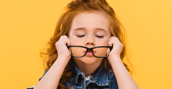 Young girl putting on glasses