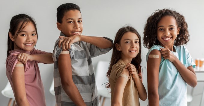 Cheerful vaccinated kids showing arms after vaccine