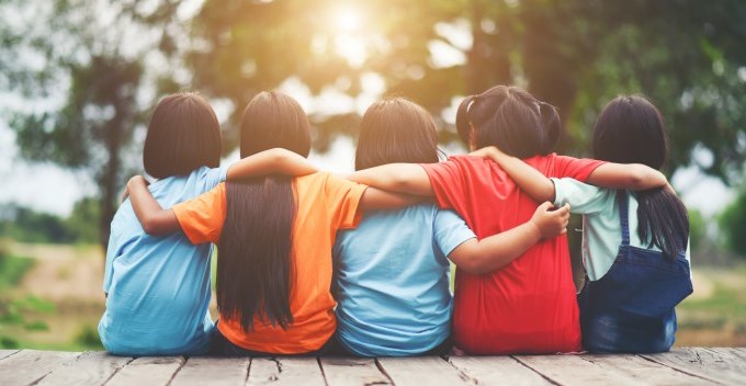 Groupe d'enfants assis ensemble et qui se tiennent par les bras