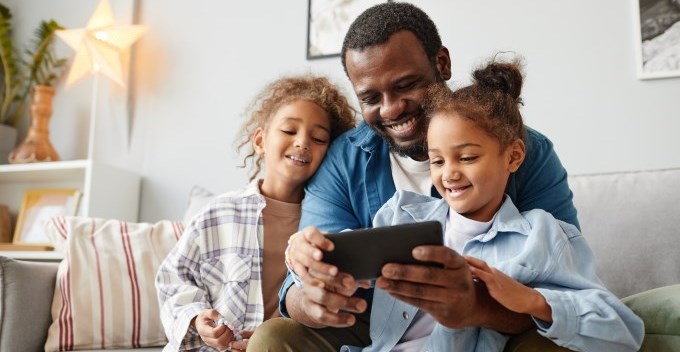 Père heureux avec deux enfants regardant une tablette